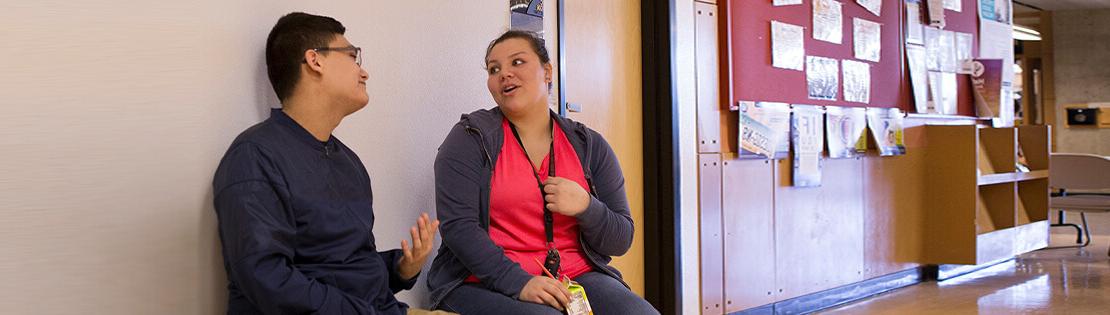 Two students chat in a Pima class hallway